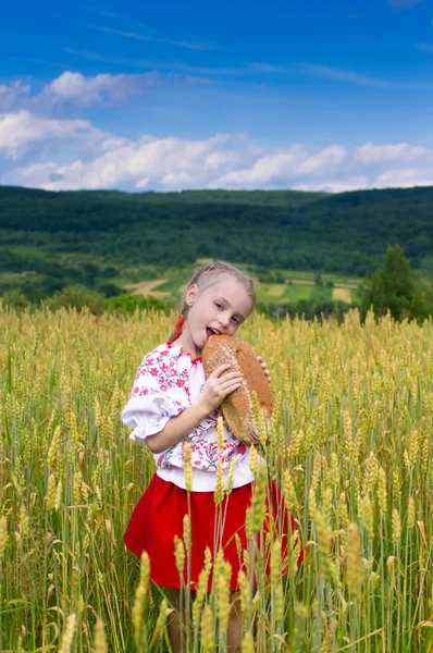Meisje met brood in het tarweveld — Stockfoto