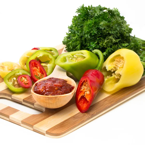 Mixture of peppers with greens on a wooden board — Stock Photo, Image