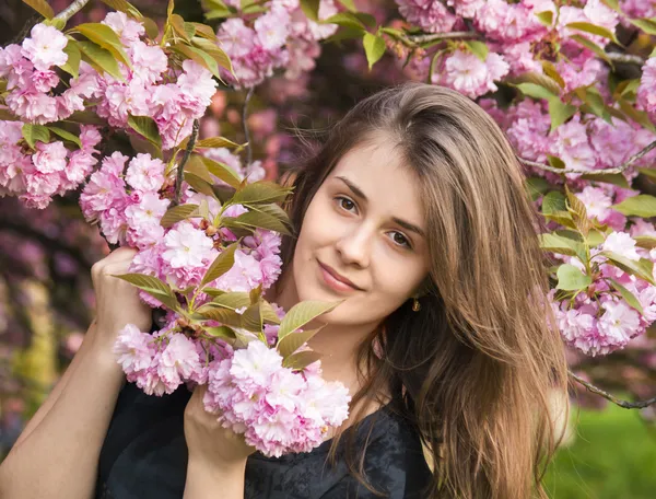 Glückliches Mädchen in den Blumen von Sakura — Stockfoto