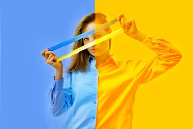 Savaşı durdurun. Genç kız, Ukrayna bayrağının arka planına karşı yüzünün önünde sarı ve mavi bir kurdele tutuyor. Saldırganlığa karşı. Dünya barışı için.