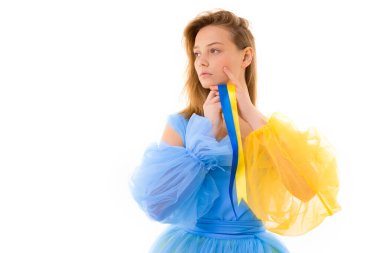 Ukrayna bayrağının sarı ve mavi sembollü elbiseli genç kız beyaz bir arka planda Ukrayna bayrağı ve yazı için bir şehir taşıyor. Anayasa Günü. Savaşı durdurun.. 