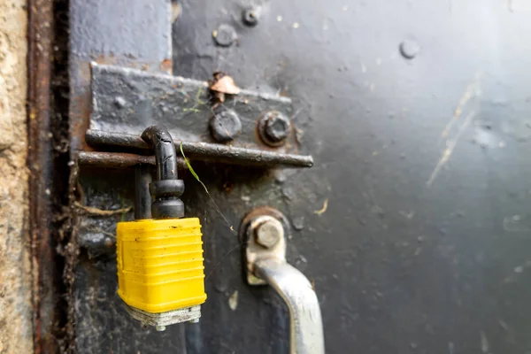 Gesloten geel slot bij zwarte stalen deur met handvat — Stockfoto