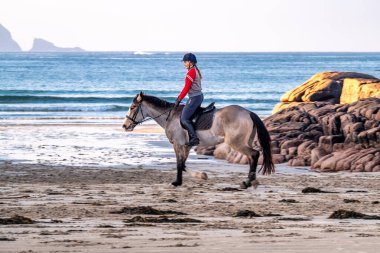 BURTONPORT, İLK DONEGAL, IRELAND - 18 ARALIK 2021: Patricia Ward sahilde atına biniyor