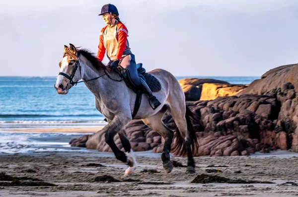 BURTONPORT, İLK DONEGAL, IRELAND - 18 ARALIK 2021: Patricia Ward sahilde atına biniyor