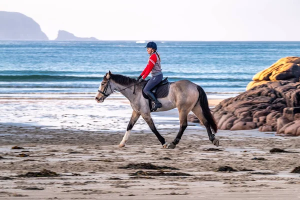 BURTONPORT, İLK DONEGAL, IRELAND - 18 ARALIK 2021: Patricia Ward sahilde atına biniyor