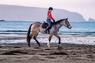 BURTONPORT, İLK DONEGAL, IRELAND - 18 ARALIK 2021: Patricia Ward sahilde atına biniyor