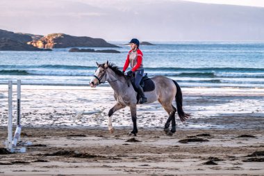 BURTONPORT, İLK DONEGAL, IRELAND - 18 ARALIK 2021: Patricia Ward sahilde atına biniyor