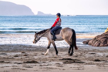 BURTONPORT, İLK DONEGAL, IRELAND - 18 ARALIK 2021: Patricia Ward sahilde atına biniyor