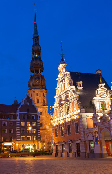 Famous House of Blackheads on the Town Square in Riga with a Church of St. Peter in the back. Latvia, after sunset. House of Blackheads, destroyed during 2 World War, was reconstructed in the 1999.