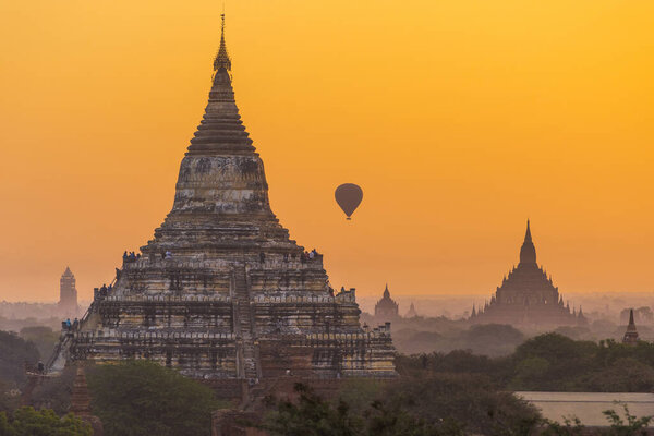 Many tourists on Shwesandaw Pagoda and in hot air balloon watching rising sun in Bagan, Myanmar