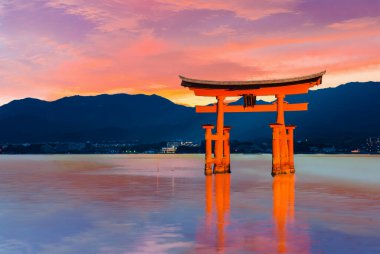 Gün batımından kısa bir süre sonra Japonya 'nın Itsukushima Tapınağı yakınlarındaki Miyajima adasındaki suya yansıyan büyük yüzen kapı (O-Torii) dramatik ve canlı bir gökyüzü ile birlikte.