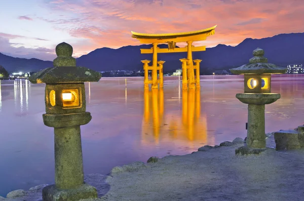 日落时分 日本石岛附近的三岛岛上 一个巨大的浮动大门 Torii 在水面上反射着光芒 湖岸上点亮了灯笼 天空生动壮观 — 图库照片