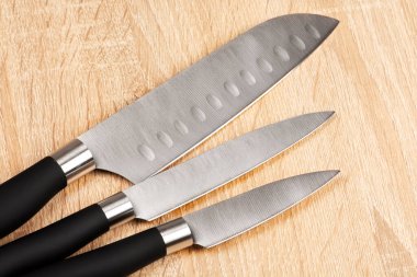 Close-up set of steel kitchen knives on wooden table