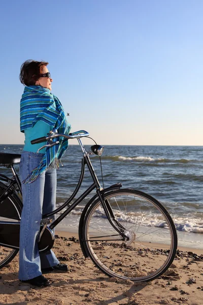 Woman in blue, bike and shawl at sea shore — Stock Photo, Image