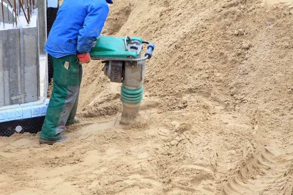 Arbeiter auf der Baustelle arbeitet mit Kompressionswerkzeug — Stockfoto