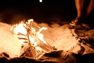 Sumbawa adasındaki plajda ateş yakan turistin yakın çekim görüntüsü.