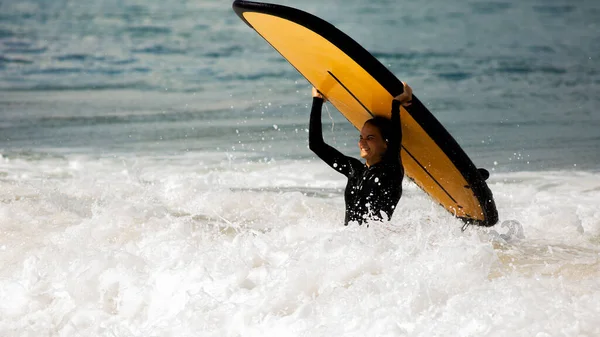 Güzel bir kız sörf tahtasıyla duruyor — Stok fotoğraf