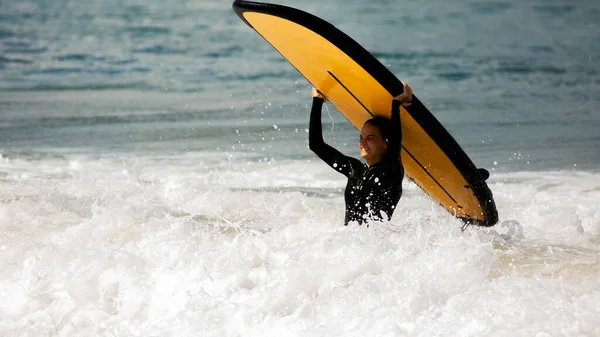 Beautiful girl stands with a surfboard — Stock Photo, Image