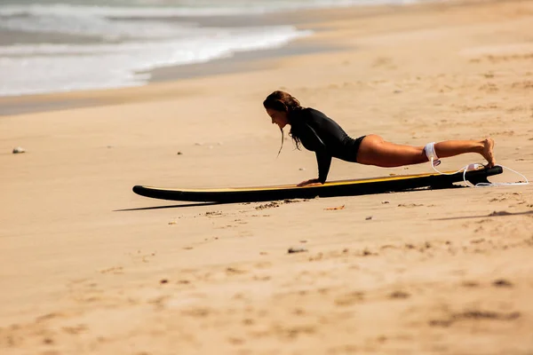 Krásná dívka vstát na surfu na písku — Stock fotografie