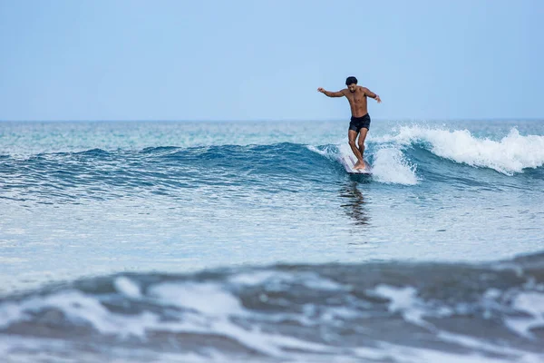 Surfista cavalcando un longboard sulle onde blu — Foto Stock