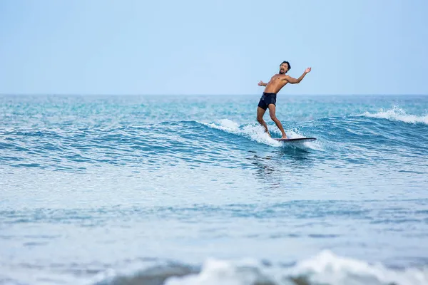 Surfista cavalcando un longboard sulle onde blu — Foto Stock