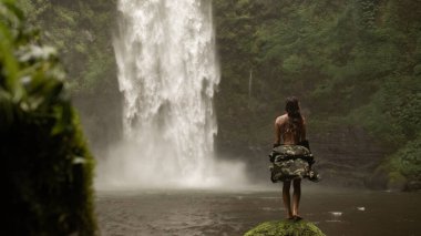 Şelalenin arka planında poz veren kadınlar.