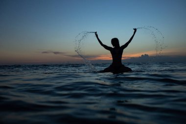 Gün batımında sörf tahtası olan güzel bir kız. yüksek kaliteli fotoğraf