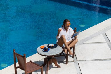 Güzel bir kadın havuz kenarında kahvaltı yapıyor. yüksek kaliteli fotoğraf