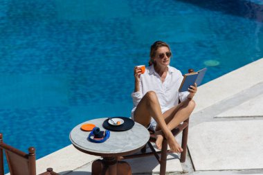 Güzel bir kadın havuz kenarında kahvaltı yapıyor. yüksek kaliteli fotoğraf