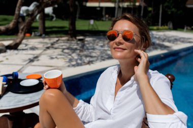 Havuz kenarında kahve içen güzel bir kadın. yüksek kaliteli fotoğraf