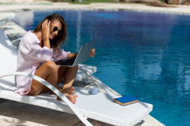 Havuzun yanındaki bilgisayarda çalışan güzel bir kadın. yüksek kaliteli fotoğraf