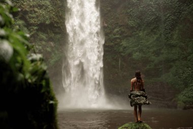 Şelalenin arka planında poz veren kadınlar.