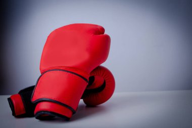 Gri arka planda kırmızı boks eldivenleri. Bir grup mavi boks eldiveninin zorlu bir rekabet ortamının iş sembolü olarak tek bir kırmızı eldivenle bir araya gelmesi gibi zorlukların üstesinden geliyor..