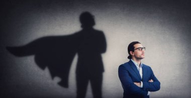 Kendine güvenen iş adamı duvara güçlü bir süper kahraman gölgesi bırakmakta kararlı görünüyor. Motive olmuş ve hırslı bir iş adamı iç gücünü gösterir. Kahraman liderlik ve güç kavramı