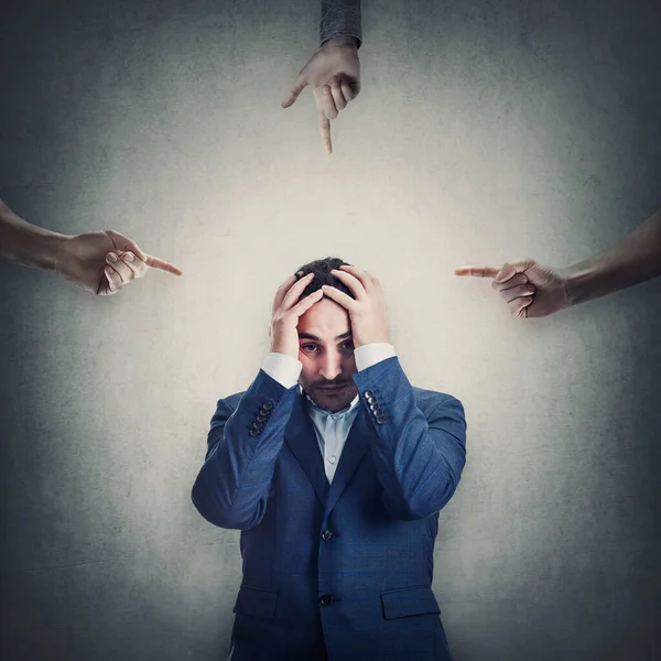 Utangaç ve çaresiz işadamı, kendisini suçlayan ve azarlayan birden fazla kişi olduğu için elleri ile başını örtüyor. Adam duygusal çöküntü ve depresyon yaşıyor, baskı altında.