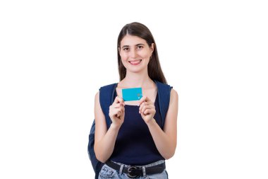 Sırt çantalı neşeli öğrenci kız kameraya kredi kartı gösteriyor, beyaz arka planda fotokopi alanı ile izole edilmiş. Memnun genç kadın bankasının reklamını yapıyor.