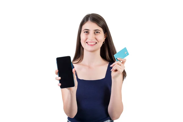一个积极的年轻女性看上去很兴奋 她拿着信用卡 拿着手机屏幕 在白色背景下与复制空间隔离 互联网移动银行概念 — 图库照片