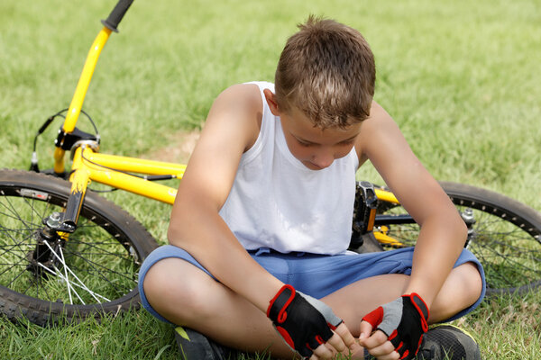 Парень, сидящий рядом с велосипедом снаружи
