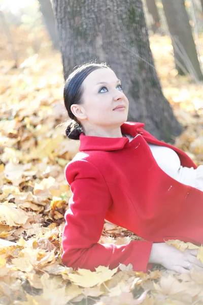 Pretty girl sitting in autumn leaves — Stock Photo, Image