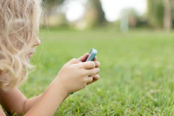 Mädchen mit Handy auf dem Gras liegend — Stockfoto