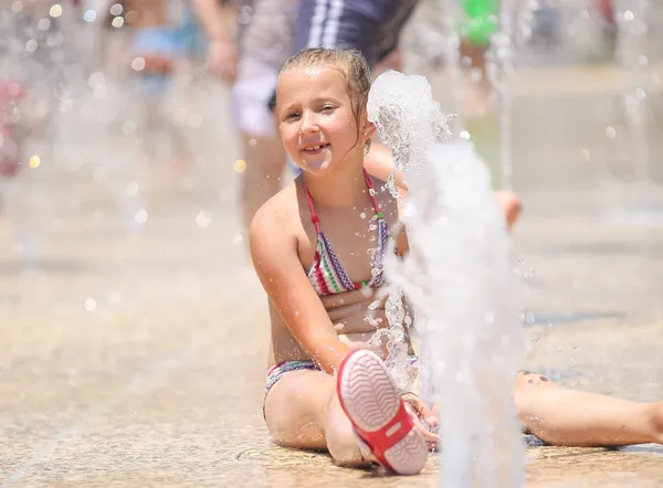 Leuk meisje u geniet van de fonteinen op een warme dag — Stockfoto