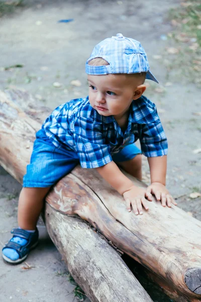 Bébé garçon assis sur une bûche — Photo