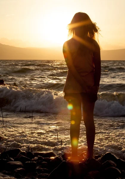 Silhouet van een meisje op het strand bij zonsondergang avond — Stockfoto