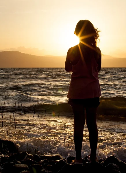 Silueta de una chica en la playa al atardecer —  Fotos de Stock