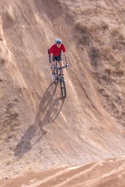 Cavaleiro em uma bicicleta, com uma colina íngreme — Fotografia de Stock