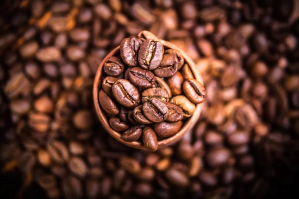 Grãos de café preto em uma xícara de madeira — Fotografia de Stock
