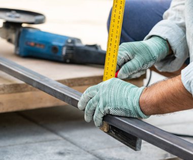 Adam metali cetvelle ölçüyor, elleri yakın çekim için.