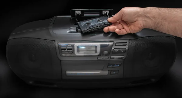 Man Zet Een Cassette Een Cassette Recorder Een Zwarte Achtergrond — Stockfoto