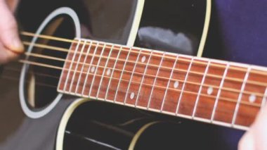 man playing guitar, hands on strings close-up