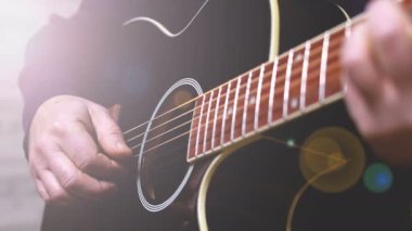 man playing guitar, hands on strings close-up